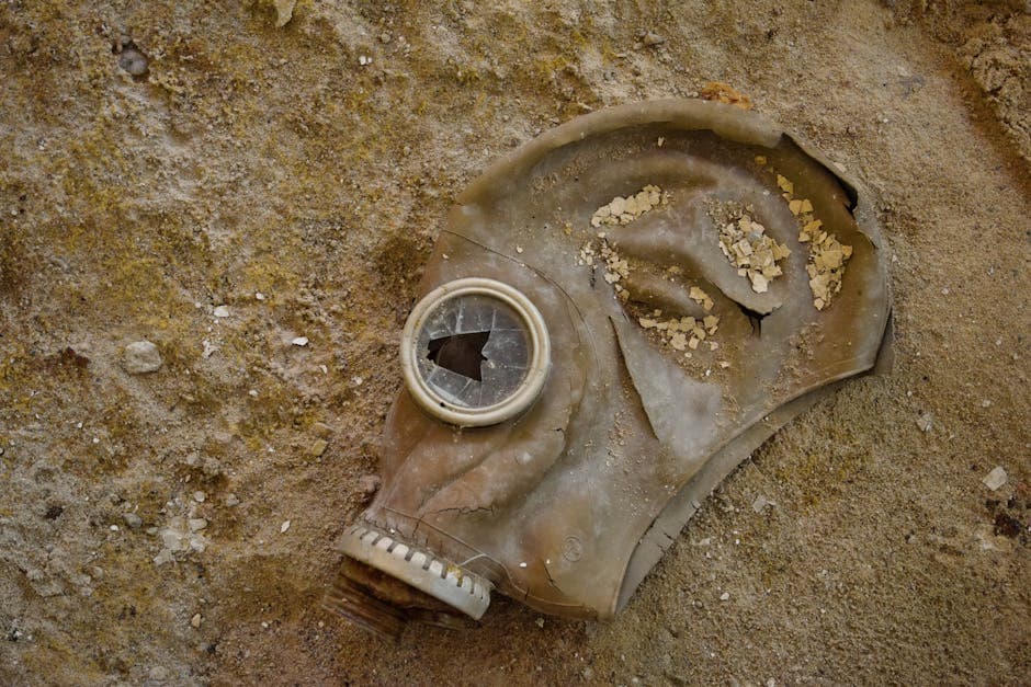 An old, broken gas mask lies on a sandy surface, evoking themes of destruction and history.