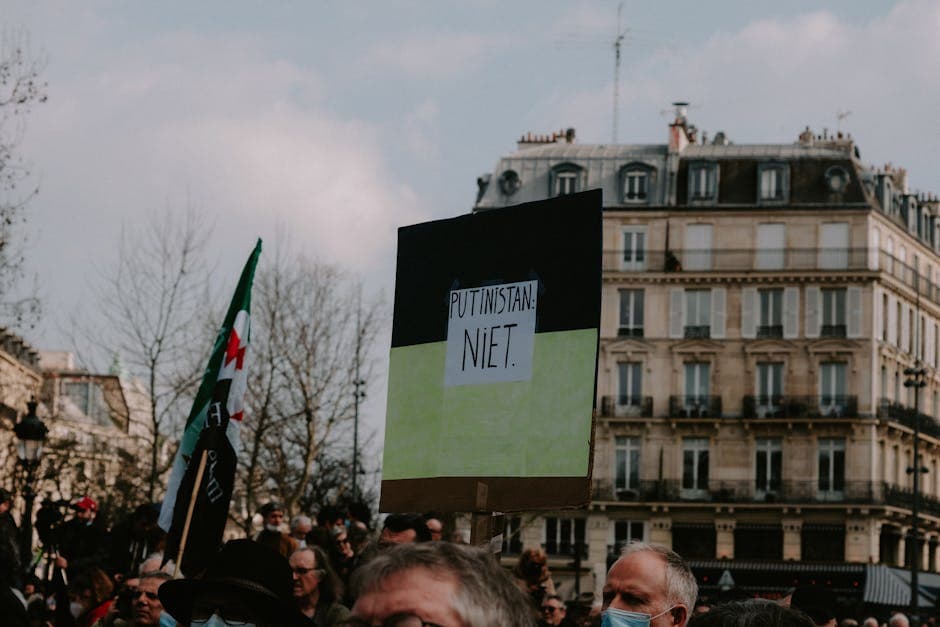 Crowd protesting with signs near city buildings, emphasizing activism and democracy.