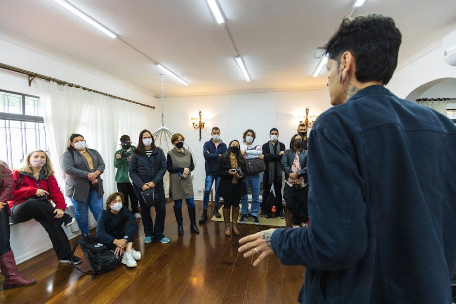 A group of adults in masks attending an indoor meeting with a speaker.