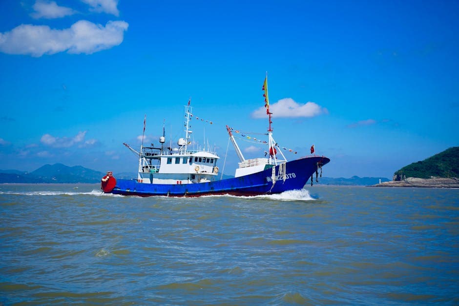 A vibrant blue fishing boat cruising on the sea under a clear, sunny sky.