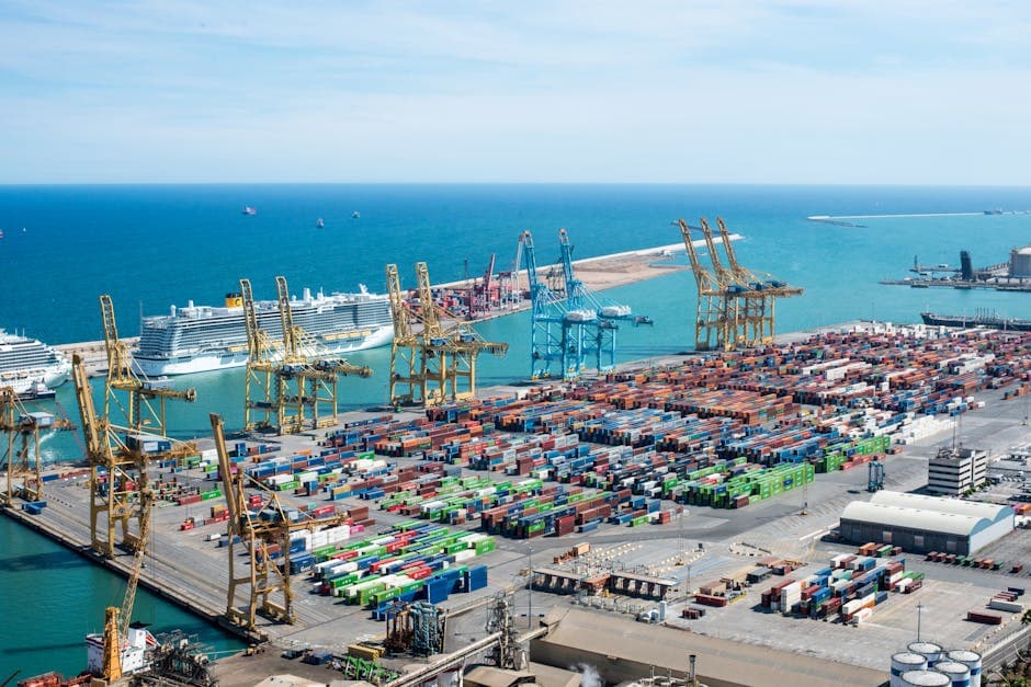 A vibrant aerial shot of Barcelona port featuring cranes, containers, and cruise ships on a sunny day.