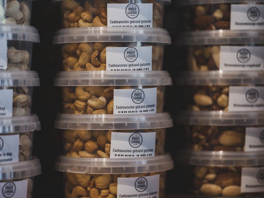 Neatly stacked transparent containers of roasted cashew nuts in a supermarket shelf.