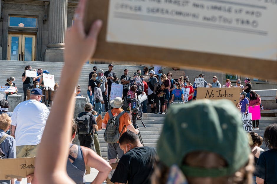 Protesters diverse people standing on stairs near building and holding placards with inscriptions about justice