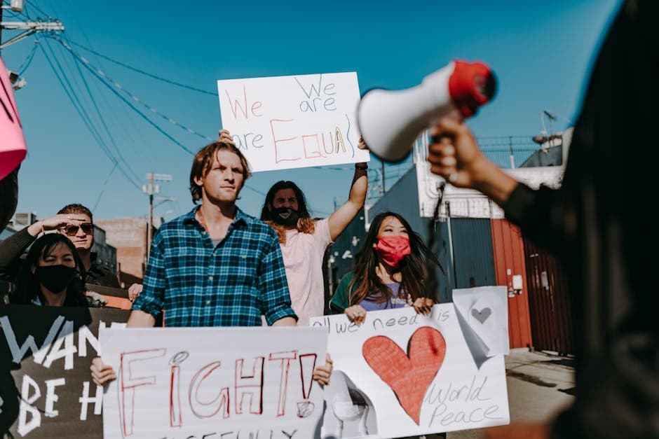 Protesters holding signs advocating equality and peace in an urban area.