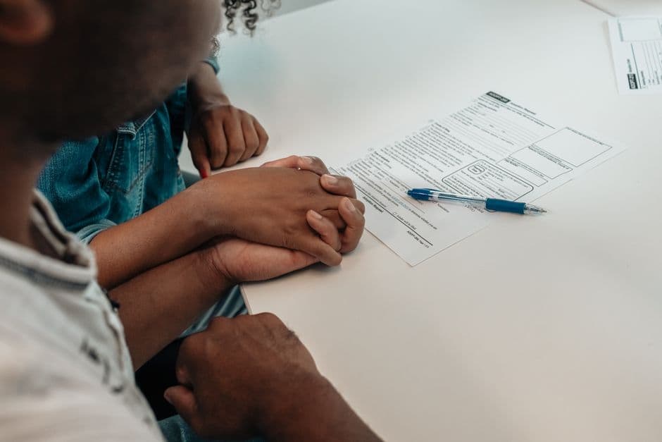 A family supports each other during an adoption process, holding hands over important documents.