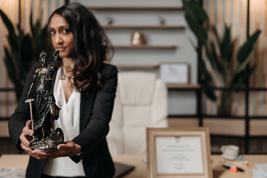 A female lawyer presenting a Lady Justice statue in a modern office setting.