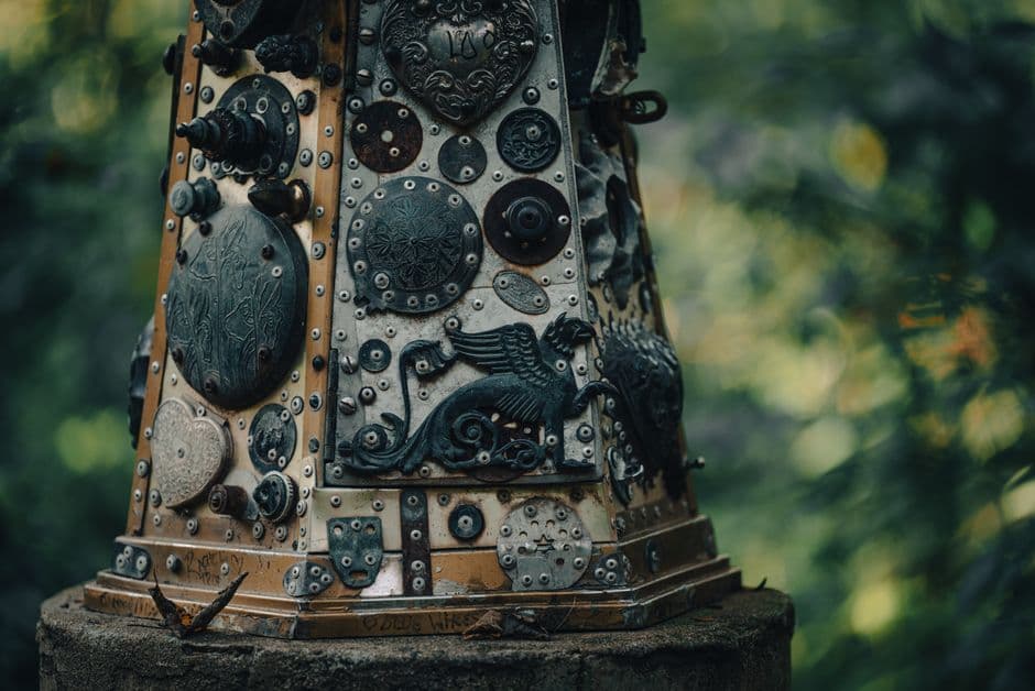 Detailed close-up of a metallic sculpture with intricate designs in an outdoor setting.