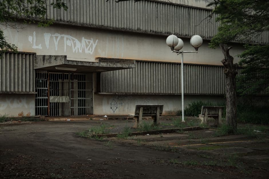 Abandoned urban structure with benches and a streetlight, featuring graffiti.