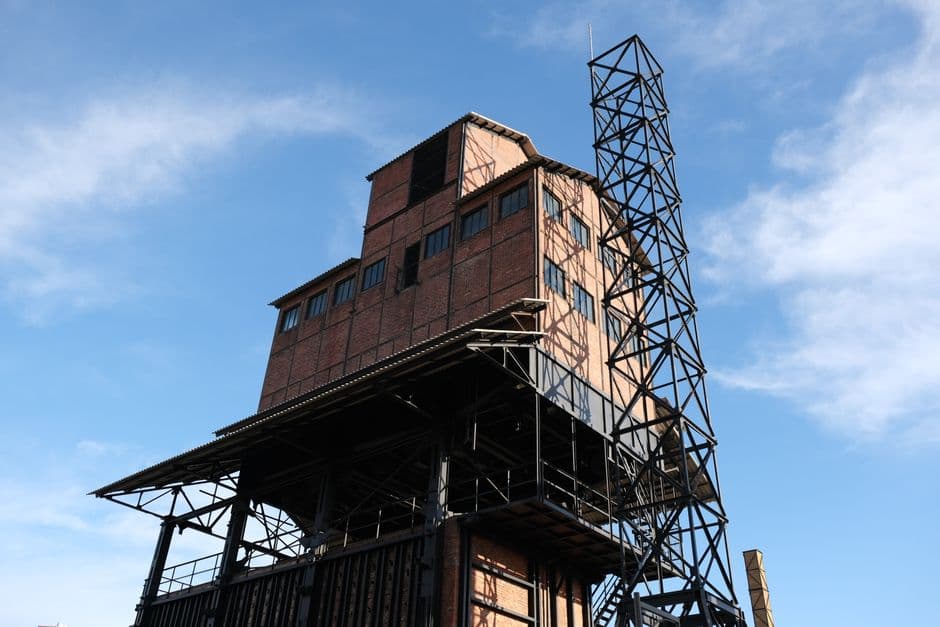 Brick industrial building featuring lattice construction against a clear blue sky.