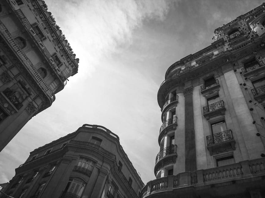 Black and white view of historic architecture with intricate balconies and a cloudy sky.