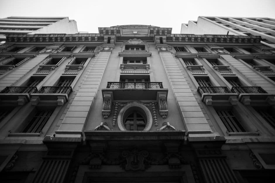 A striking black and white low angle shot of an ornate urban tenement facade showcasing architectural details.