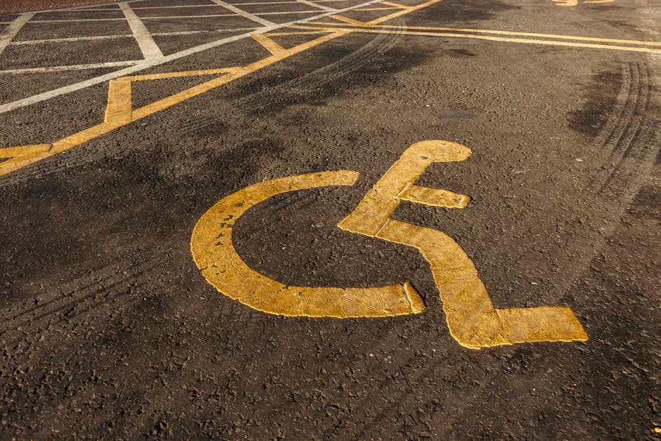 Yellow wheelchair symbol painted on asphalt in a parking lot.