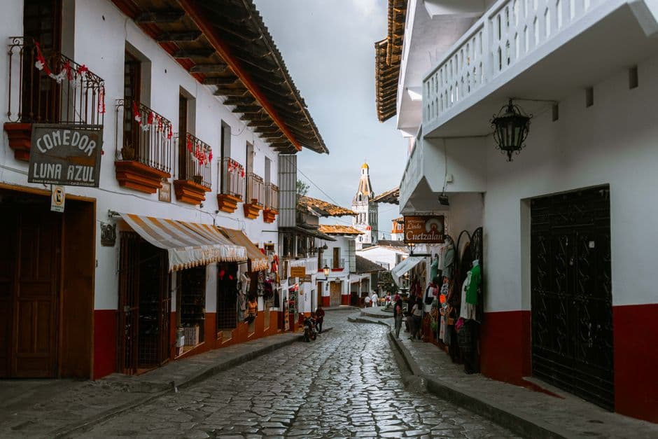 Historic cobblestone street with traditional Mexican architecture in a quaint village setting.