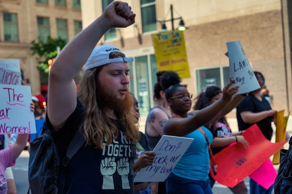 A diverse group of protestors displaying signs during a peaceful outdoor march, advocating for social change.