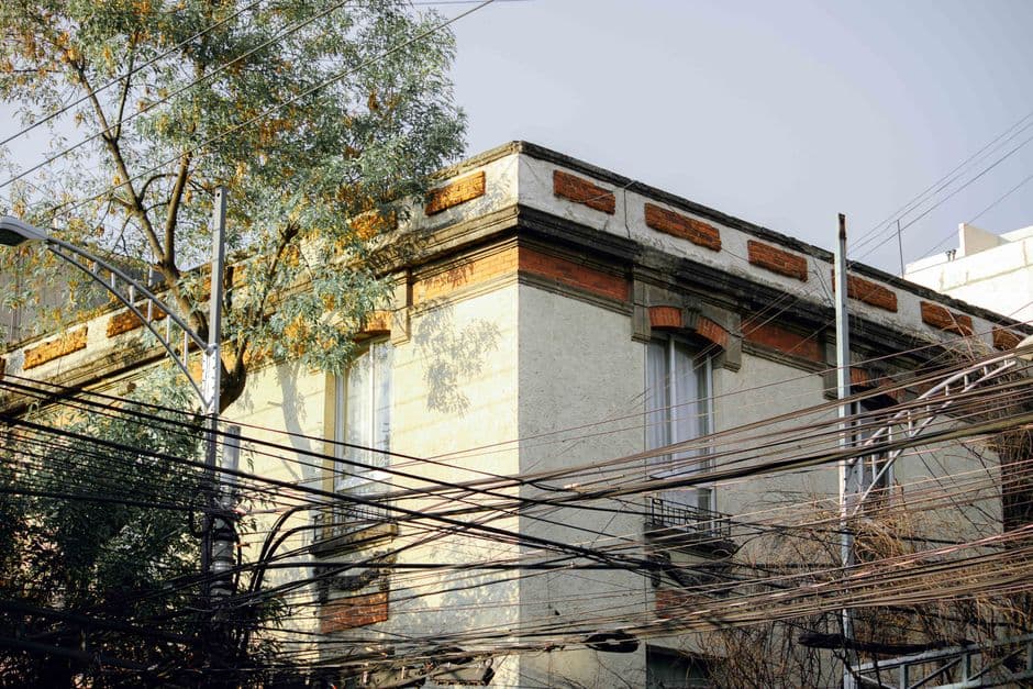 Historic building facade with dense overhead utility wires and surrounding trees.