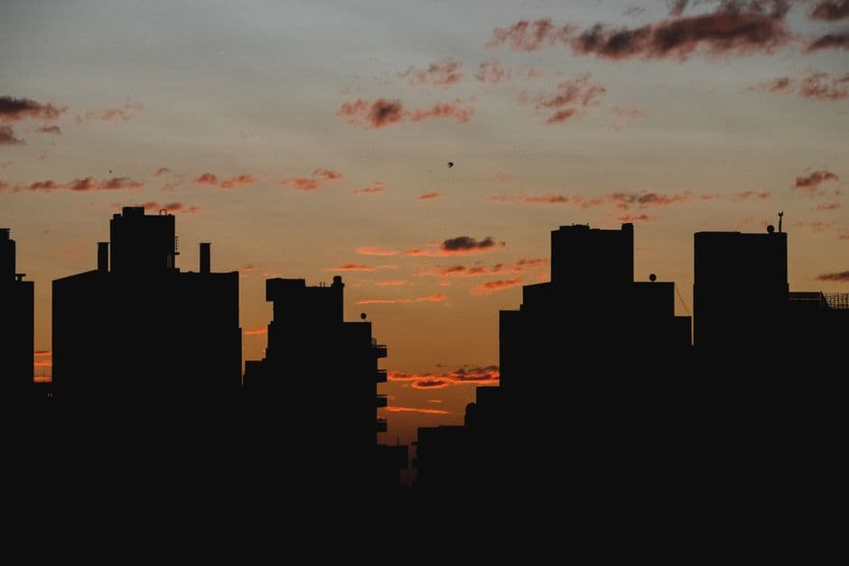 A dramatic urban skyline silhouetted against a vibrant sunset sky.