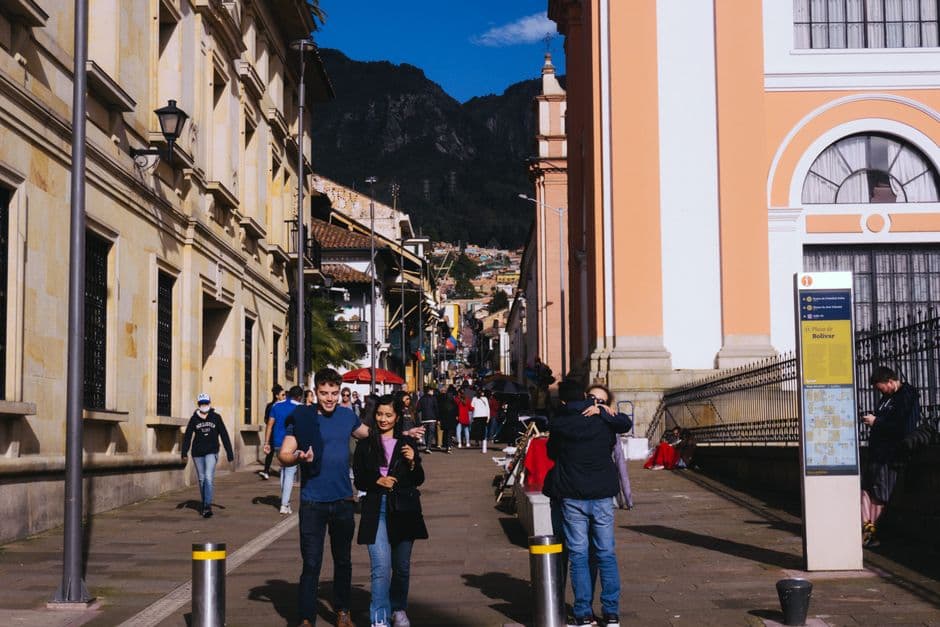 Lively street scene with people walking amidst historical buildings in a sunny urban plaza.