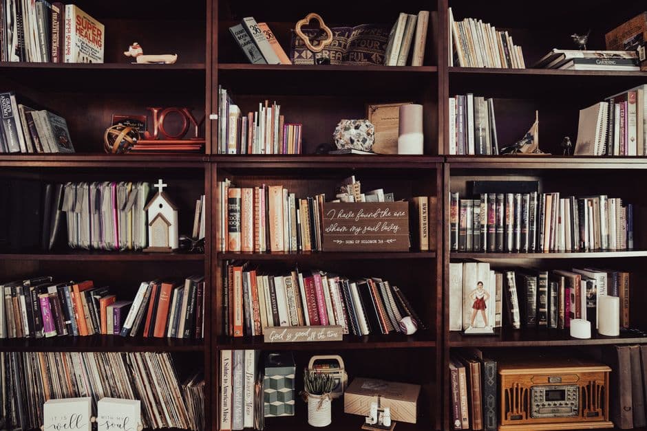 Warm-toned bookshelf filled with diverse books, religious decor, and trinkets.