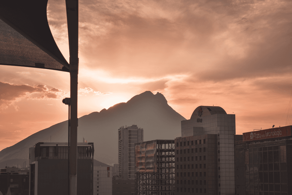 Captivating sunset over Monterrey's skyline with Cerro de la Silla silhouette, offering a serene urban scene.