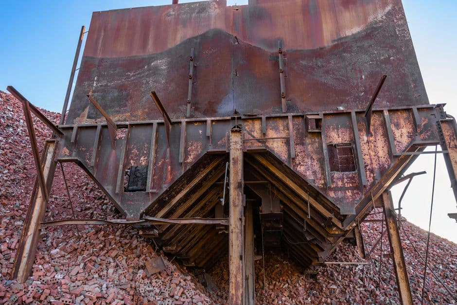 Abandoned rusty structure surrounded by piles of broken bricks, great for industrial decay themes.