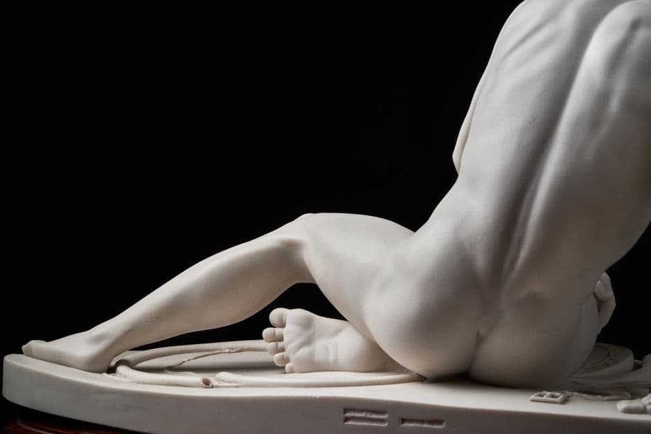 Close-up view of a marble statue's intricate details with a dark background.