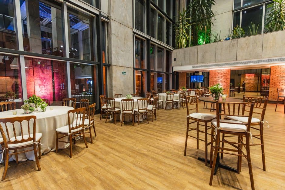 Beautifully decorated indoor venue with chairs, tables, and lush greenery for a celebration.