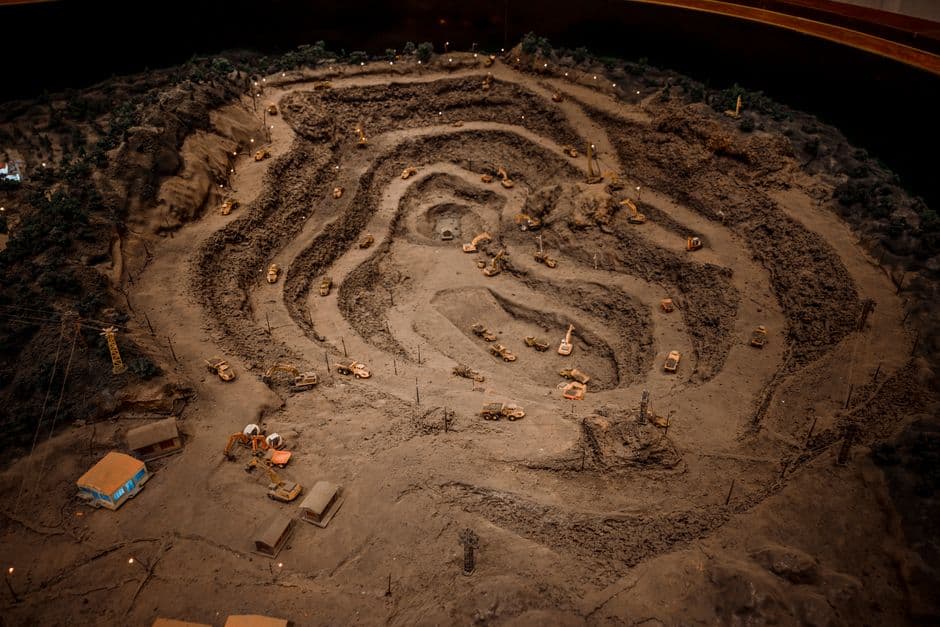 A detailed miniature model of a quarry with various construction equipment and terrain layers.