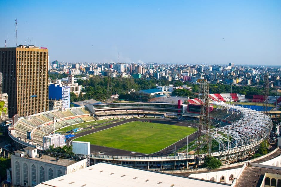 Aerial urban scene with a large stadium and city skyline, vibrant atmosphere.