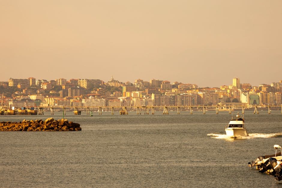 A charming coastal cityscape with a boat cruising on calm waters at sunset.