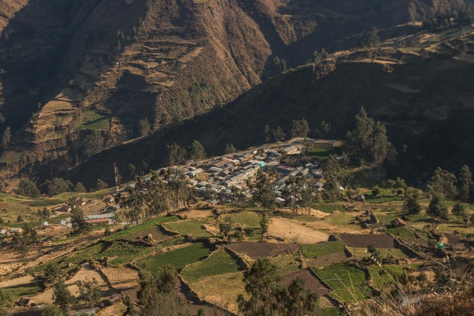 Explore the aerial view of a vibrant village nestled in Huancavelica, Peru, showcasing agricultural landscapes.