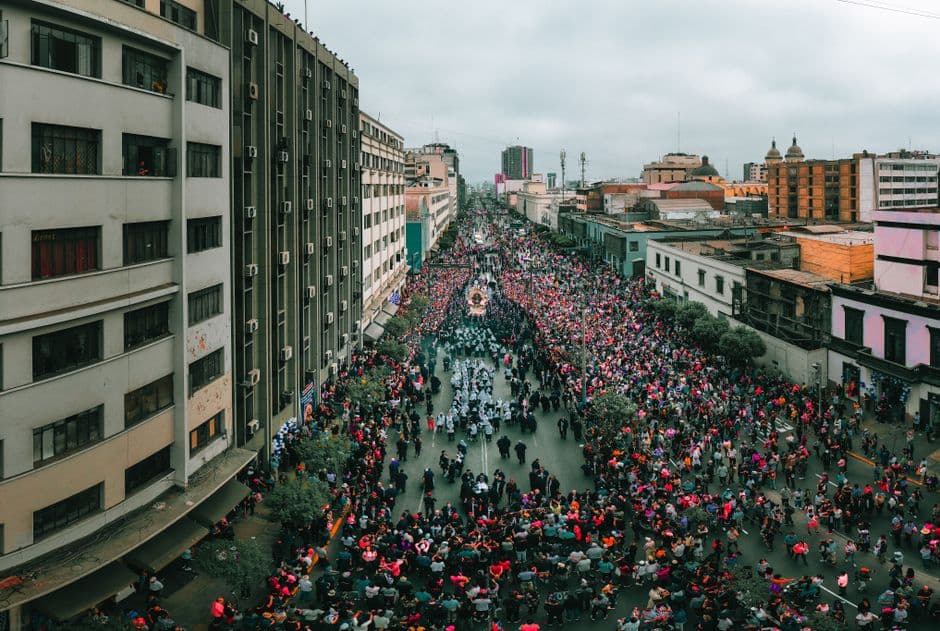A bustling aerial view of a religious procession in Lima, Peru's urban landscape.