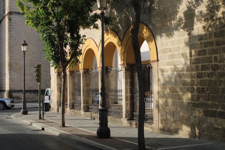 Charming street scene with arched facade and trees in Jerez de la Frontera, Spain, on a sunny day.