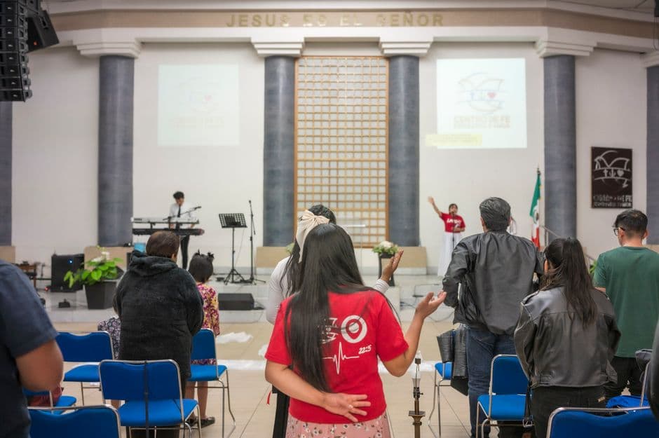 A diverse group of people praying and worshipping inside a church during a religious event.