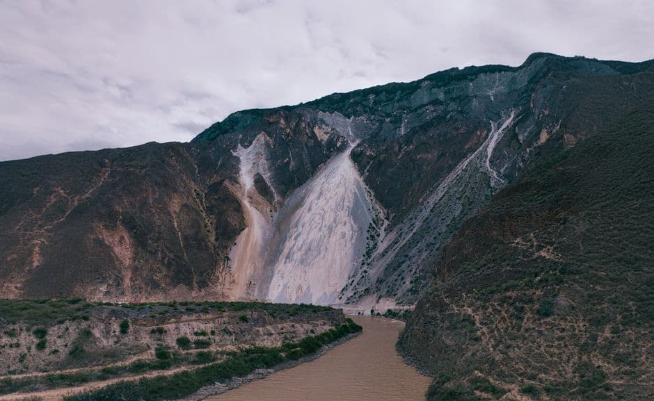 Dramatic landscape of mountain and river in Nyingchi, Tibet, China showcasing rugged nature and geological formations.