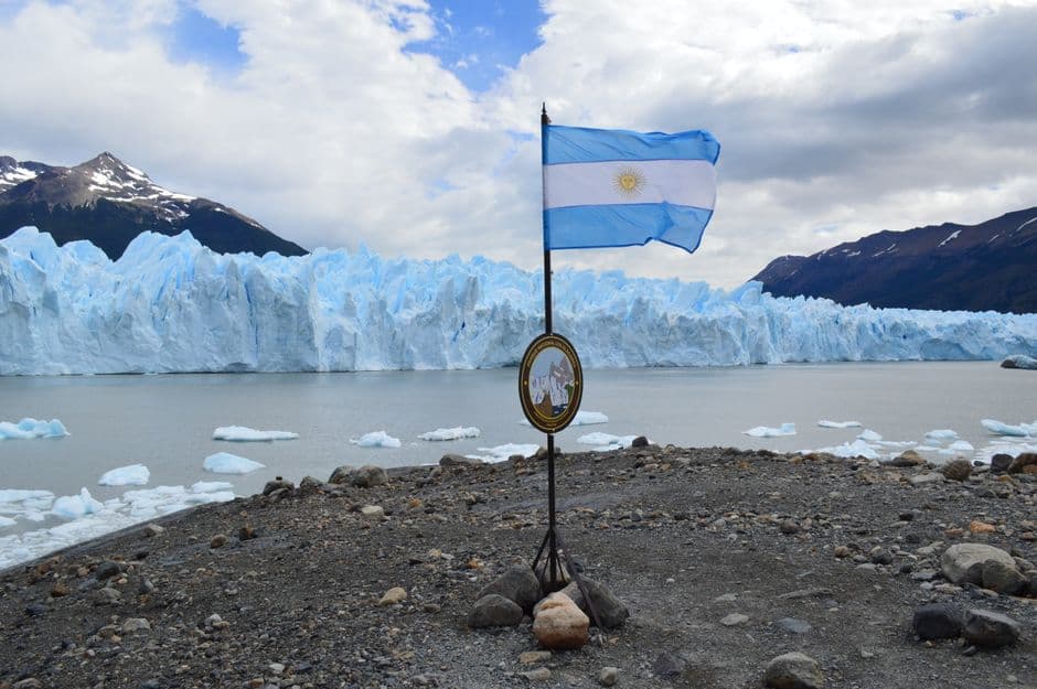 The iconic Perito Moreno Glacier with the Argentine flag, a stunning UNESCO World Heritage Site in Patagonia.