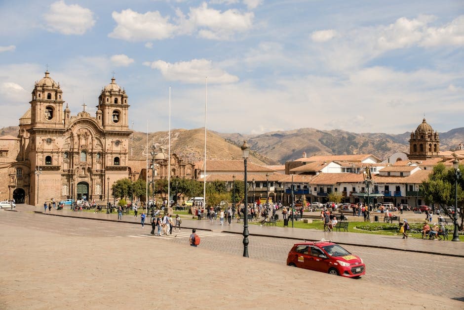 A vibrant view of a historic square in Cusco, Peru, featuring a cathedral, people, and street life.