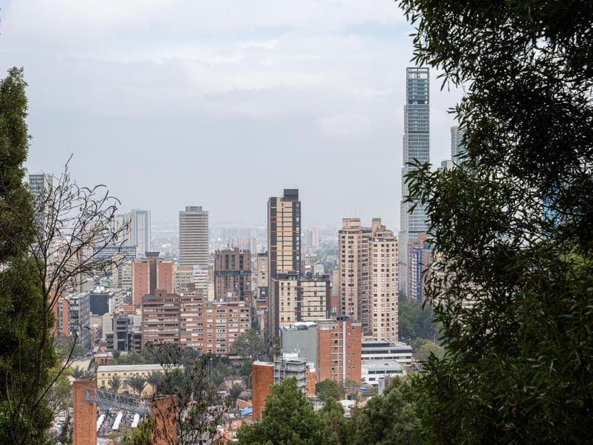 A scenic view of Bogotá's skyline surrounded by greenery, showcasing urban architecture and nature.
