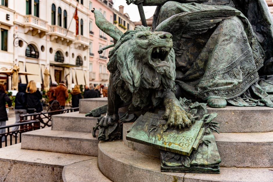 Bronze winged lion statue on a pedestal in Venice with tourists in the background.