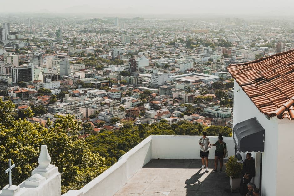 Overlooking cityscape from an elevated white terrace with people enjoying the view.
