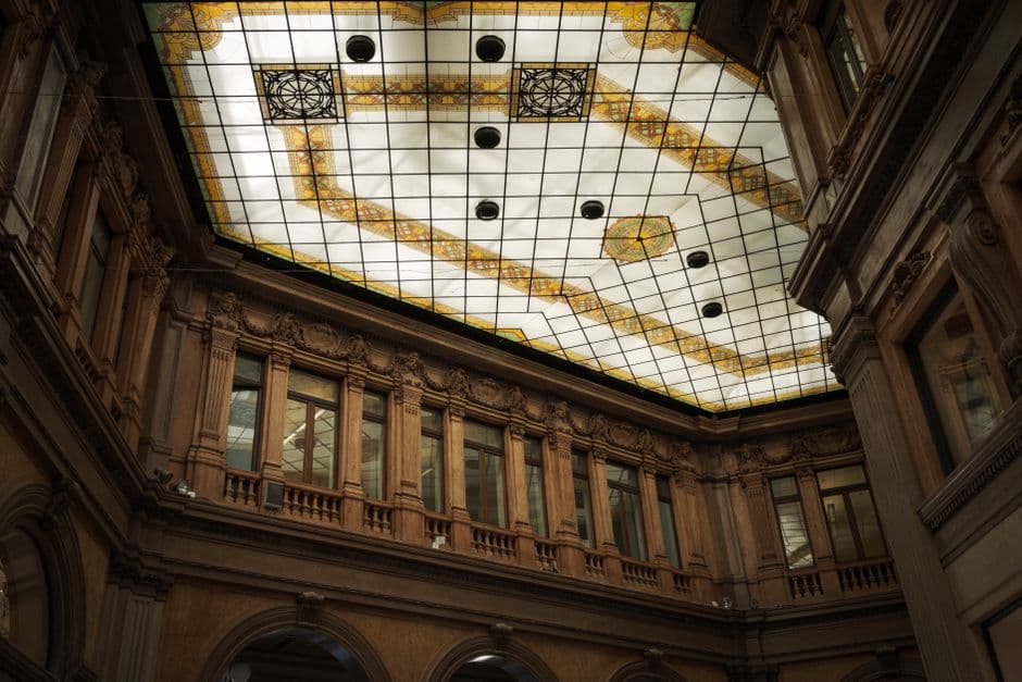 View of a historic interior atrium with intricate stained glass ceiling design, showcasing architectural elegance.