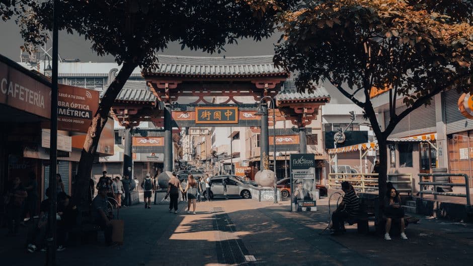 A bustling street scene in Chinatown showing a traditional archway and people walking.