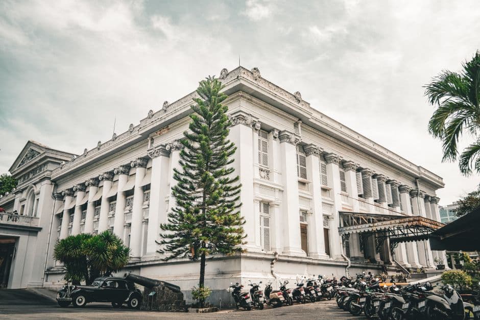 A view of the iconic Ho Chi Minh City Museum, showcasing its neoclassical architecture with a lineup of motorbikes in the foreground.