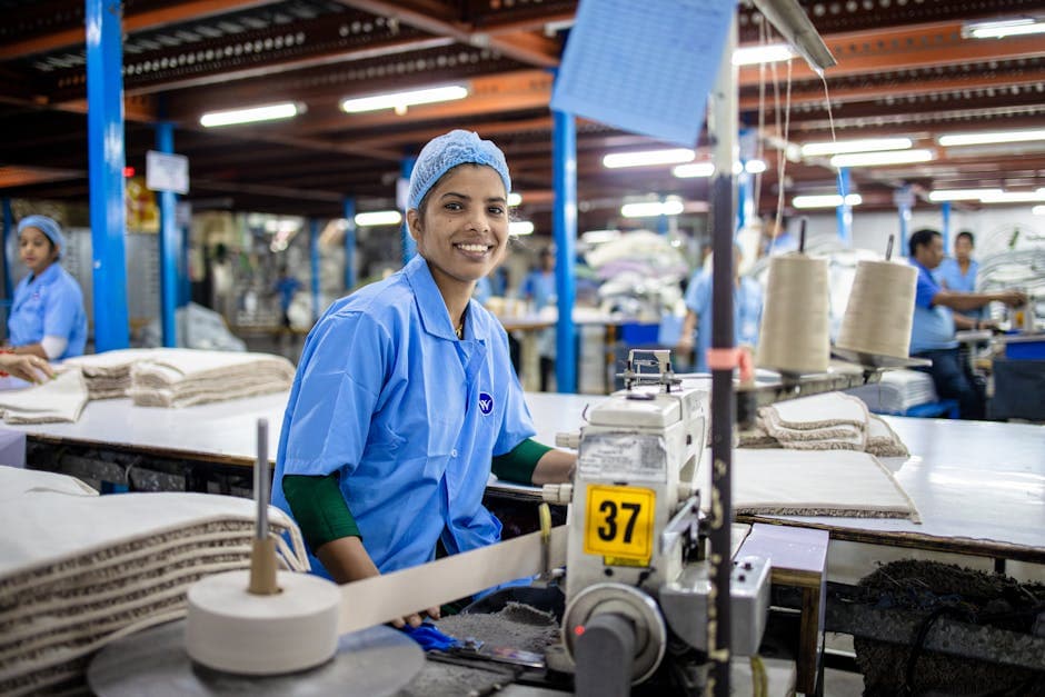 Smiling female textile worker at sewing machine in a modern factory.