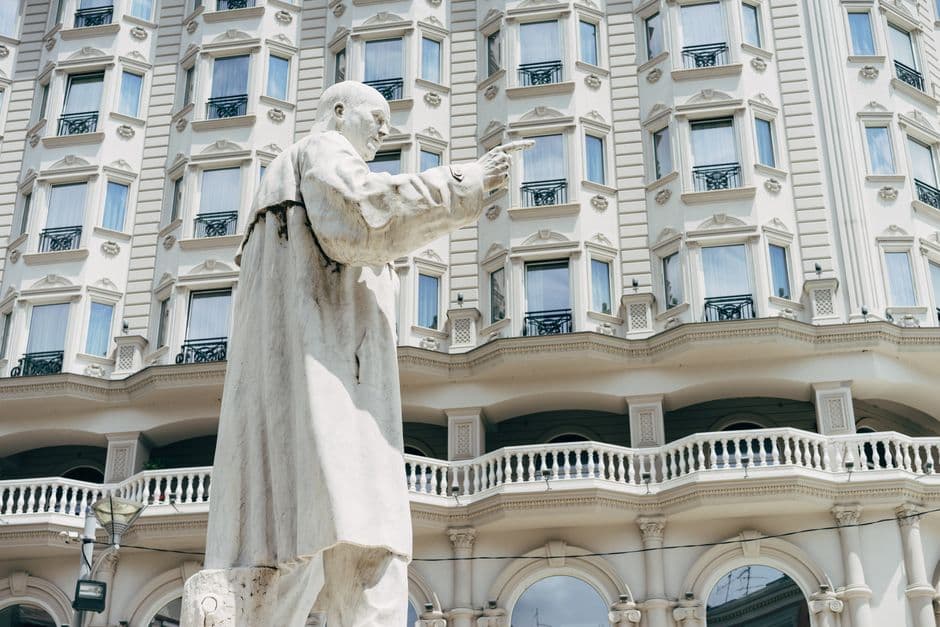 Monumental statue in front of a historic building in Skopje, North Macedonia, featuring classical architectural details.
