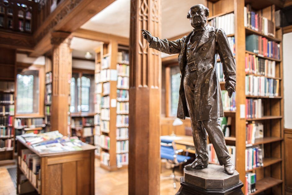 A historic statue inside a classic library in Hawarden, Wales, surrounded by shelves of books.