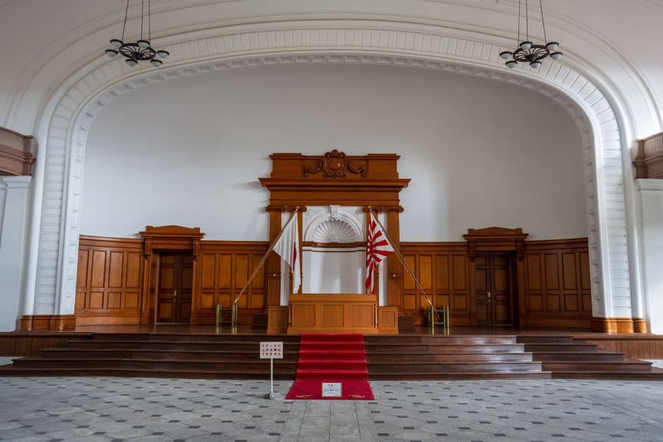 Empty wooden stage with traditional flags and red carpet in a vintage hall, creating a classic and formal ambiance.