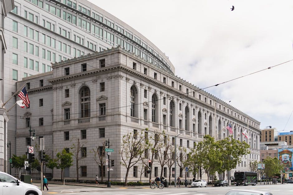 Elegant neoclassical courthouse in San Francisco with American flags outside.