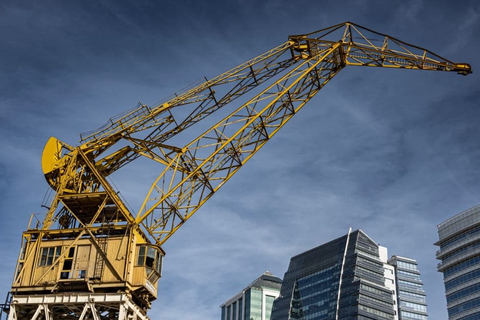 Yellow construction crane against modern buildings in Buenos Aires, with a clear blue sky.