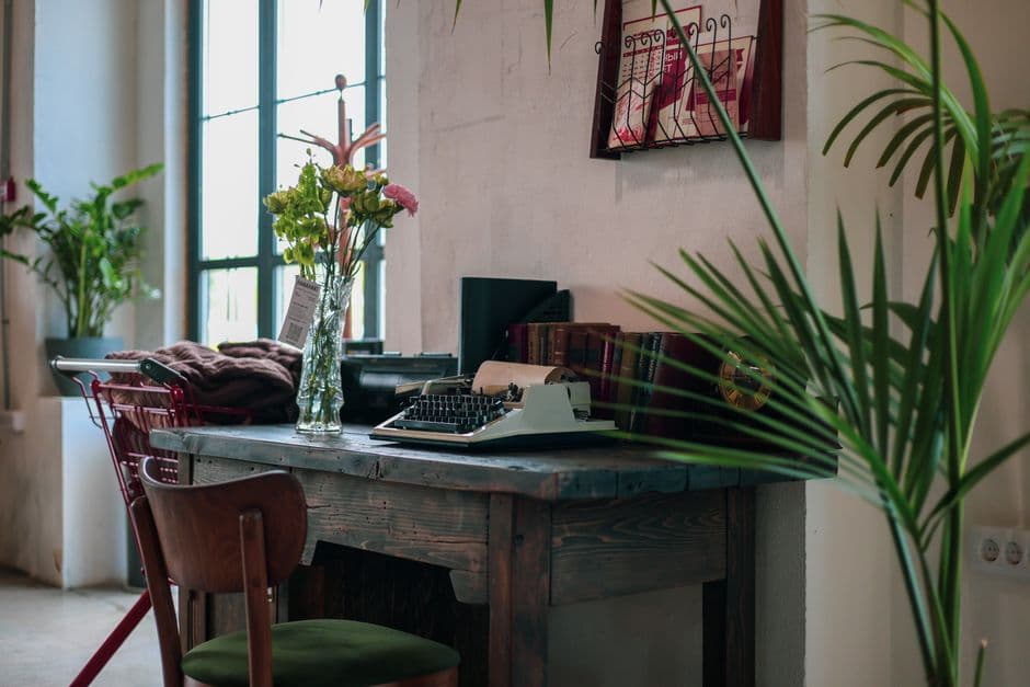 Inviting home office featuring a vintage typewriter, wooden desk, and lush indoor plants.
