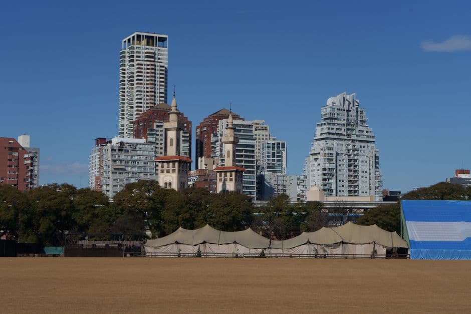 Panoramic view of Buenos Aires skyline with modern buildings and clear skies, featuring a field in the foreground.